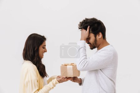 Photo for Young indian woman giving present box to her boyfriend isolated over white background - Royalty Free Image