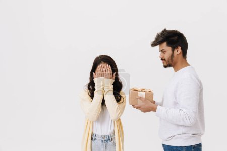 Téléchargez les photos : Est asiatique jeune homme et femme souriant et posant avec boîte cadeau isolé sur fond blanc - en image libre de droit