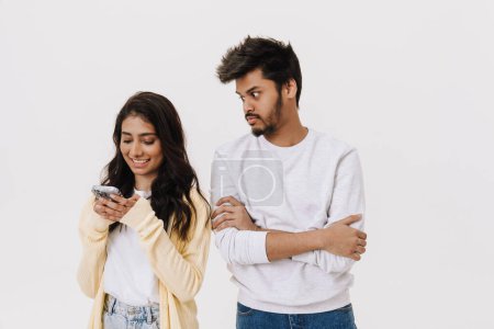 Téléchargez les photos : Est asiatique jeune homme et femme souriant et en utilisant un téléphone portable ensemble isolé sur fond blanc - en image libre de droit