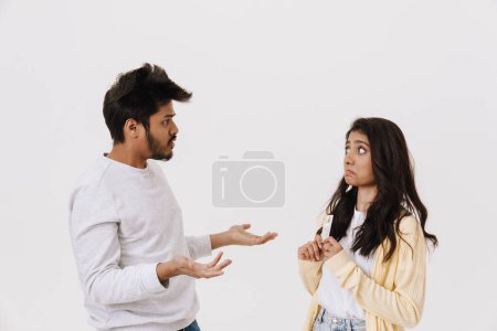Téléchargez les photos : Jeune couple indien gesticulant tout en posant avec carte de crédit isolé sur fond blanc - en image libre de droit