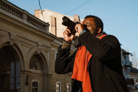 Téléchargez les photos : Noir mi-homme prenant des photos tout en marchant dans la rue de la ville à l'extérieur - en image libre de droit