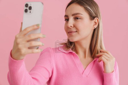 Photo for Young beautiful white woman smiling and taking selfie photo on cellphone standing isolated over pink background - Royalty Free Image