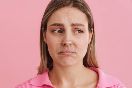Téléchargez les photos : Jeune femme blanche contrariée portant chemise fronçant les sourcils et regardant triste debout isolé sur fond rose - en image libre de droit