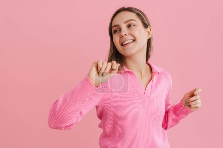 Foto de Joven chica feliz en blusa rosa bailando con la boca abierta sobre fondo rosa aislado - Imagen libre de derechos