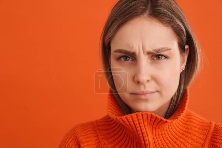Téléchargez les photos : Jeune belle femme blanche portant pull fronçant les sourcils et regardant triste debout isolé sur fond rouge - en image libre de droit