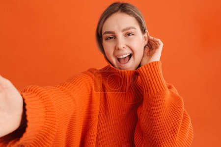 Photo for Young white excited woman wearing sweater smiling and taking selfie photo standing isolated over red background - Royalty Free Image