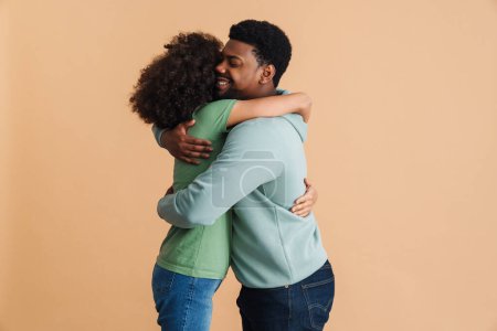 Téléchargez les photos : Noir homme et femme exprimant bonheur et étreinte ensemble isolé sur fond beige - en image libre de droit