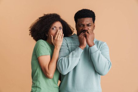 Photo for Black man and woman expressing fear and looking at camera isolated over beige background - Royalty Free Image