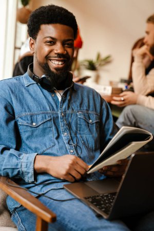 Téléchargez les photos : Homme barbu noir note tout en utilisant un ordinateur portable dans le café à l'intérieur - en image libre de droit