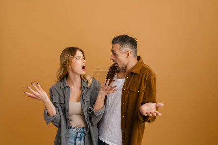 Photo for White young man and woman expressing surprise and throwing their hands aside standing isolated over yellow background - Royalty Free Image
