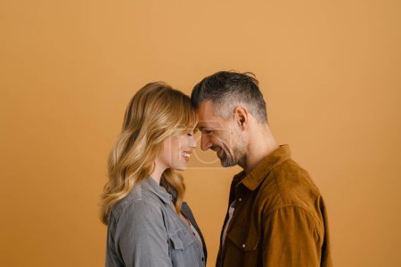Téléchargez les photos : Blanc heureux couple souriant tout en posant tête à tête isolé sur fond beige - en image libre de droit