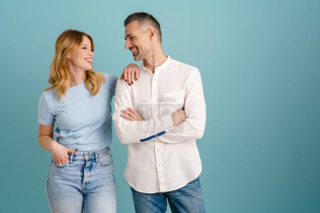 Photo for White happy couple smiling and looking at each other isolated over blue background - Royalty Free Image