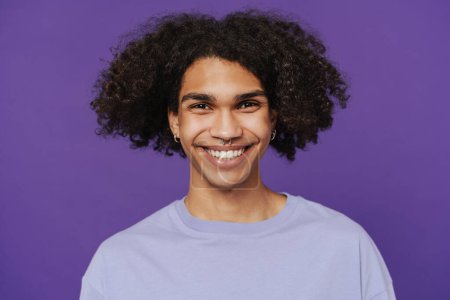 Foto de Young happy smiling handsome latin curly man with piercing looking at camera over isolated violet background - Imagen libre de derechos