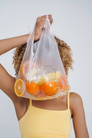 Foto de Young black woman wearing underclothes holding bag with fruits isolated over white background - Imagen libre de derechos