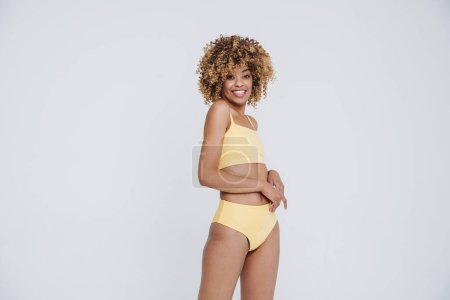 Téléchargez les photos : Young black woman wearing underclothes smiling and posing at camera isolated over white background - en image libre de droit