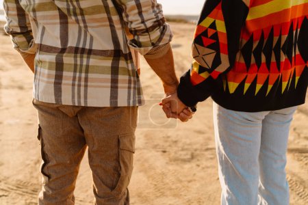 Téléchargez les photos : Jeune couple blanc tenant la main en marchant au bord de la mer en automne - en image libre de droit