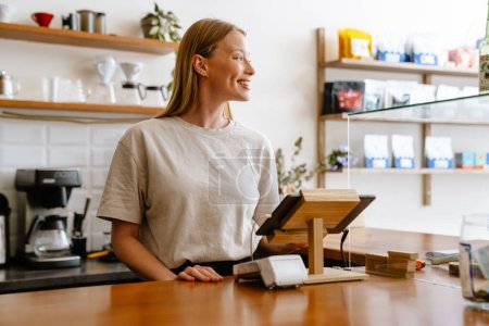 Foto de Mujer rubia barista blanca que trabaja con la tableta en el café en el interior - Imagen libre de derechos