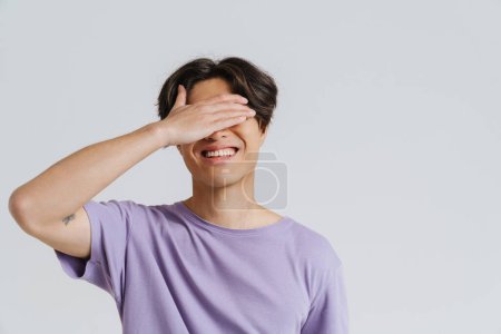 Photo for Young asian man wearing t-shirt smiling and covering his eyes isolated over white background - Royalty Free Image