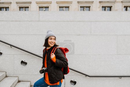 Foto de Hermosa alegre joven asiático mujer con mochila y cámara subir la escaleras en ciudad calle - Imagen libre de derechos
