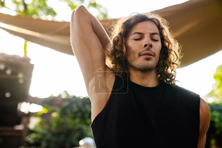 Photo for Young curly white man doing workout and stretching his body outdoors - Royalty Free Image
