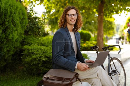 Foto de Jengibre hombre europeo que trabaja con el ordenador portátil mientras está sentado en el parque de verano - Imagen libre de derechos