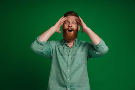 Téléchargez les photos : Ginger white man with beard expressing surprise at camera isolated over green background - en image libre de droit