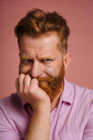 Téléchargez les photos : Ginger sad man with beard frowning and looking at camera isolated over pink background - en image libre de droit