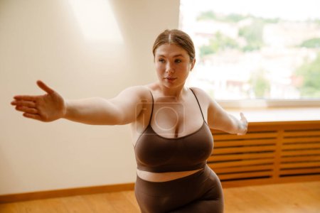 Téléchargez les photos : Gingembre jeune femme faire de l'exercice pendant la pratique du yoga à l'intérieur - en image libre de droit