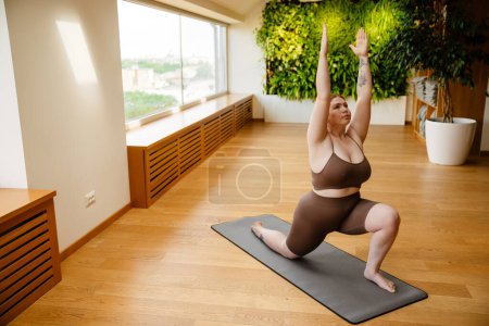 Photo for Ginger young woman doing exercise during yoga practice indoors - Royalty Free Image