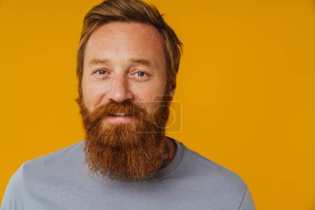 Photo for Bearded happy man posing at camera while standing isolated over yellow background - Royalty Free Image