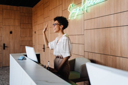 Téléchargez les photos : Femme d'affaires d'âge moyen souriant tout en travaillant sur ordinateur de bureau à la réception - en image libre de droit