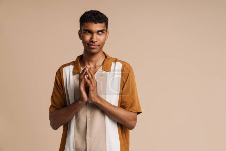 Photo for Perplexed black man gesturing while looking at camera isolated over beige background - Royalty Free Image