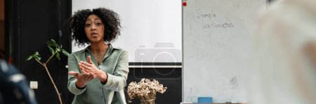 Téléchargez les photos : Middle aged african female teacher explaning new topic to students in class - en image libre de droit