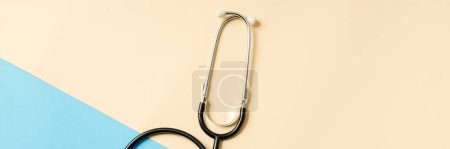 Photo for Overhead view of a badge with a stethoscope lying on a beige and blue background in the studio - Royalty Free Image