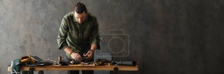 Photo for Middle aged man leathersmith working at his workshop, standing at the table - Royalty Free Image