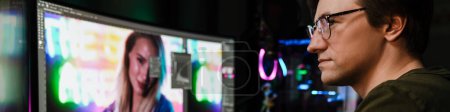 Foto de Vista trasera de un joven editor de video blanco sentado frente a una pantalla grande trabajando en un montaje de video en interiores - Imagen libre de derechos