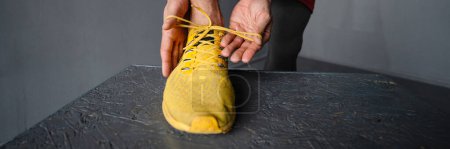 Photo for Young shirtless sportsman tying his shoe laces while working out indoors - Royalty Free Image