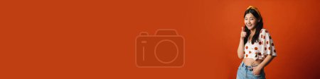 Téléchargez les photos : Souriant jeune asiatique femme en été vêtements debout sur fond orange - en image libre de droit