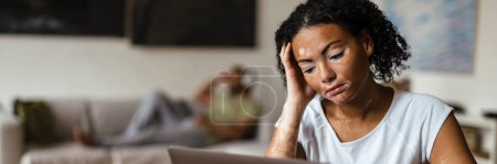 Téléchargez les photos : Femme avec vitiligo travaillant avec un ordinateur portable tout en étant assis à la table à la maison - en image libre de droit