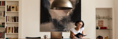 Foto de Mujer con vitiligo examinando planificador mientras trabaja en casa - Imagen libre de derechos