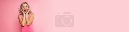 Téléchargez les photos : Portrait d'une jeune femme blonde excitée souriante portant un maillot de bain debout sur un fond mural rose - en image libre de droit