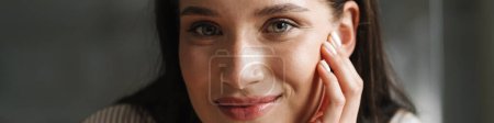 Téléchargez les photos : Jeune femme brune souriante et regardant la caméra à l'intérieur - en image libre de droit