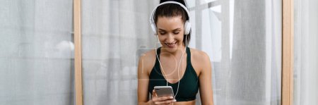 Photo for White woman listening music with headphones and cellphone while working out at home - Royalty Free Image