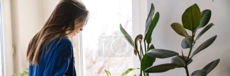 Téléchargez les photos : Jeune femme fleuriste s'occupant des plantes en pot à l'intérieur, arrosant les plantes - en image libre de droit