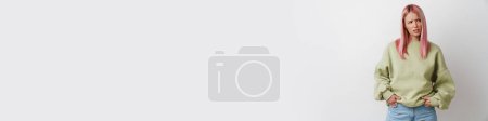 Téléchargez les photos : Jeune femme mécontente avec les cheveux roses fronçant les sourcils et regardant de côté isolé sur fond blanc - en image libre de droit