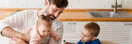Foto de Padre blanco jugando con sus hijos mientras desayuna en casa - Imagen libre de derechos