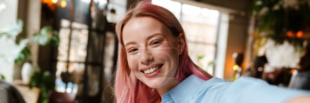 Téléchargez les photos : Jeune belle femme aux cheveux roses prenant selfie photo tout en buvant du café dans le café - en image libre de droit