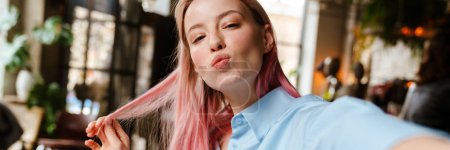 Téléchargez les photos : Jeune belle femme aux cheveux roses prenant des photos selfie tout en étudiant dans un café - en image libre de droit