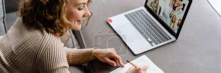 Téléchargez les photos : Femme blanche écrivant des notes et utilisant un ordinateur portable tout en étant allongé sur le canapé à la maison - en image libre de droit