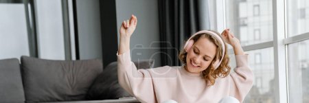 Téléchargez les photos : Femme blanche écoutant de la musique avec des écouteurs assis sur le sol à la maison - en image libre de droit